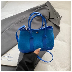Detail view of royal blue suede tote bag with leather straps and silver buckle