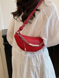 Sac bandoulière tressé rouge avec chaîne argentée et perles sur robe blanche