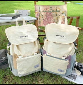 Outdoor camping scene showing large capacity patchwork backpack on grass with camping gear