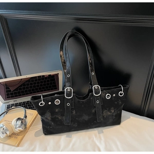 Close-up of black tote bag with silver eyelets, buckles and metallic studs on strap