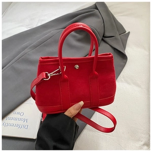 Detail view of red suede handbag with silver metal buckle and detachable shoulder strap