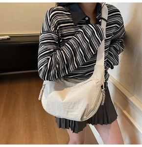 Dettaglio della borsa beige che mostra il tiretto intrecciato e l'etichetta laterale