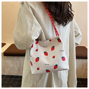 Detailed view of white strawberry print tote bag with textured fabric and braided handle