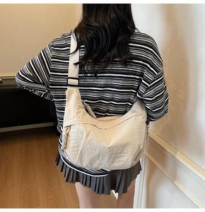 Vista posteriore di un modello che indossa la borsa a tracolla in nylon beige con cinturino
