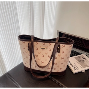 Detail of large tote bag with deer and floral prints on a leather bench in office setting
