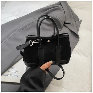 Detail of black suede tote bag with leather trim and magnetic silver clasp closure