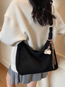 Black vintage half-moon tote bag with coffee cup charm and woven tassel detail