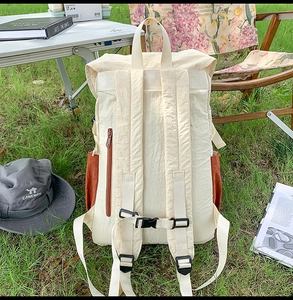 Detail view of the beige nylon backpack back featuring adjustable straps and security pocket