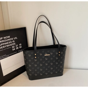 Detail of black tote bag with vintage deer monogram pattern and golden metal hardware