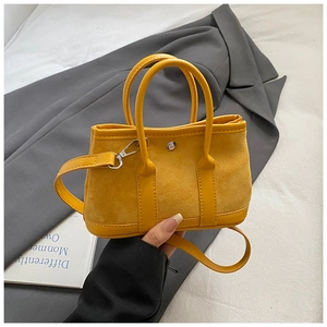 Detailed macro of yellow suede mini tote bag with silver rivet and shoulder strap