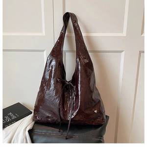 Close-up of glossy crinkled leather tote bag with silver heart charm and bow detail