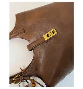 Detail of dark brown vintage oil wax leather handbag with golden twist lock closure