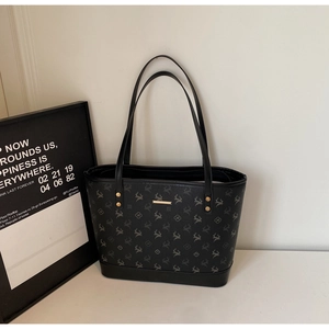 Detail of black printed tote bag with deer pattern, gold metal bar and rivet accents