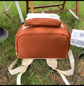 Detail view of the durable brick orange nylon fabric and reinforced straps of the backpack