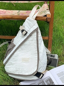 Waterproof white nylon crossbody bag with fashion label shown on an outdoor grass background