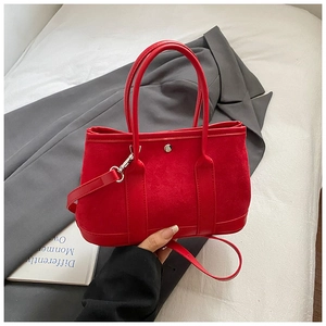 Detail view of red suede tote bag showing silver metal clasp and leather strap texture