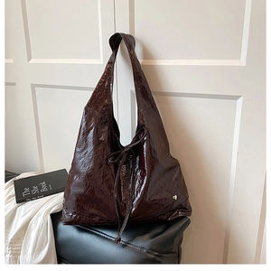 Detail of dark brown wrinkled leather tote with drawstring bow and heart metal charm