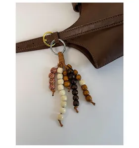 Detail of handmade wooden bead tassel charm featuring earth tones on a leather bucket bag