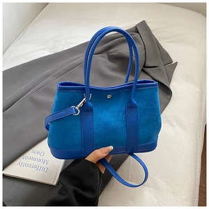Detail of blue textured tote bag featuring dual handles and silver metallic hardware lock
