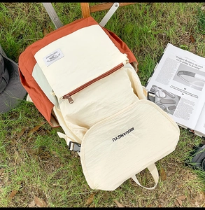 Outdoor camping scene showing a tricolor large capacity canvas backpack on green grass
