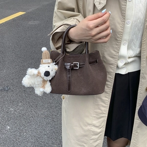 Close-up of woven dark brown texture with leather strap and cute plush bear charm