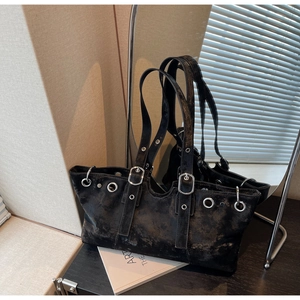 Detail of vintage black tote bag with silver eyelets and adjustable buckle straps