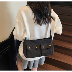Detailed view of the black multi-pocket crossbody bag worn by a model on stairs