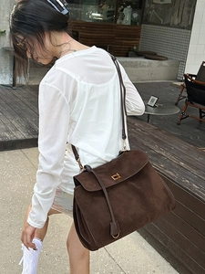 Dunkelbraune matte Ledershopper mit Golddetails, präsentiert von einem Model im Freien