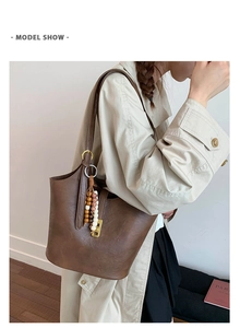 Close-up of a vintage brown leather bucket bag with decorative beaded tassel detail
