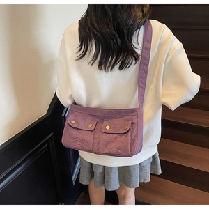 Detail of purple nylon crossbody bag with dual snap pockets shown on model's shoulder