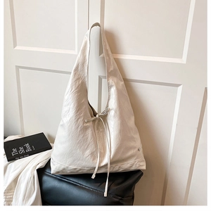 Detail of soft cream white tote bag featuring decorative bow and crinkled leather texture