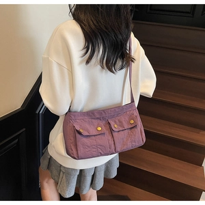 Purple nylon shoulder bag with utility pockets shown on model with casual white sweatshirt