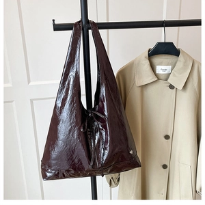 Close-up of deep wine red wrinkled patent leather hobo bag hanging on a black hanger