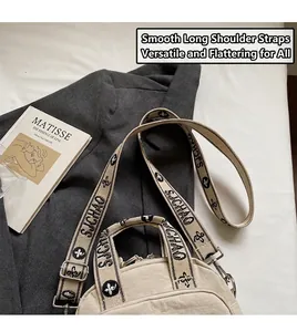 Detail der beige Umhängetasche mit breitem Logo-Gurt, Griffen und Metallteilen