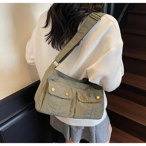Detail of army green nylon shoulder bag featuring front pockets and adjustable wide strap