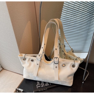 Detail of cream shoulder tote bag featuring silver eyelets and adjustable buckle straps