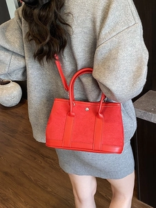 Red suede and leather tote bag worn by a model in a grey knit sweater for a chic look