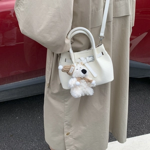 White woven texture bucket bag with silver buckle and cute plush puppy charm on trench coat