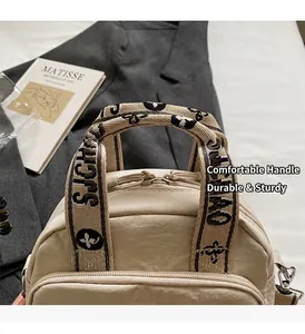 Detail der hellbeigen wasserabweisenden Nylontasche mit Jacquard-Gurtband und Reißverschlüssen