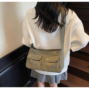 Lifestyle view of olive green nylon crossbody bag with large front pockets and shoulder strap