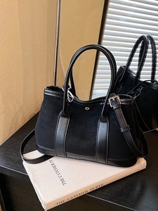 Chic black tote bag with matte leather stitching and adjustable strap on a mirror surface