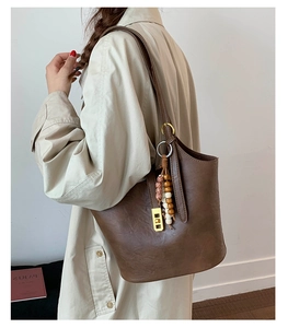 Detail of vintage brown bucket bag with gold hardware and ethnic wooden beads accessory