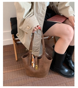 Detail of vintage brown leather bucket bag with boho wooden beads and gold hardware