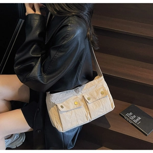 Detail of beige canvas shoulder bag with double front pockets and gold metallic buckles