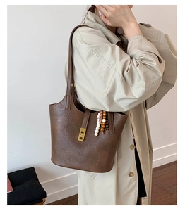Detail of vintage brown leather bucket bag with colorful ethnic beads and gold buckle