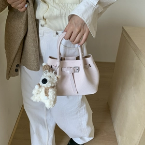 Detail of light pink bucket bag with embossed texture and a cute teddy bear charm