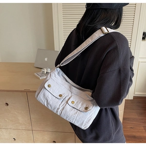 Back view of person wearing an off-white canvas crossbody bag with dual front pockets