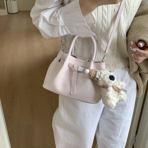 Detail of light pink crocodile pattern bucket bag with a cute plush bear charm accessory