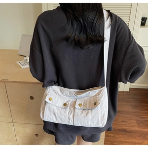 Detail view of light grey canvas shoulder bag with dual pockets and metal buttons