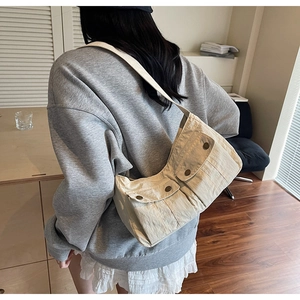Detail of off-white canvas crossbody bag featuring pleated texture and dual front utility pockets